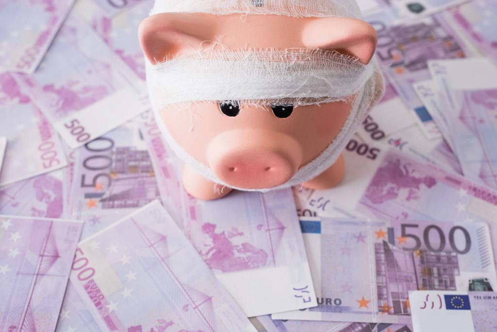 High angle view of piggy bank with bandage on money - Photo, Image