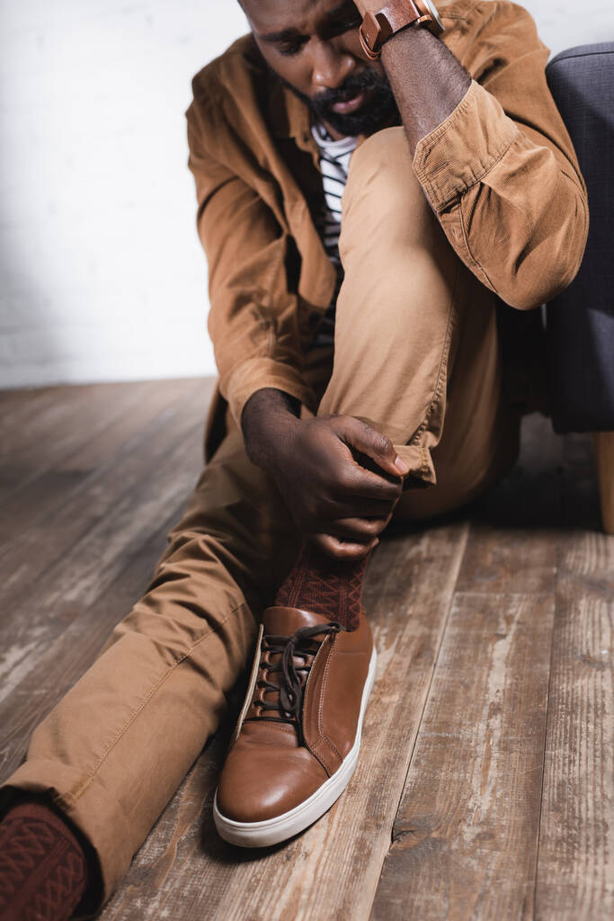 Selectieve focus van Afro-Amerikaanse man zittend op de vloer met gesloten ogen - Foto, afbeelding