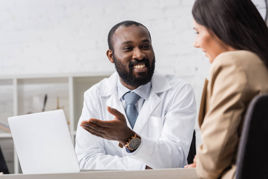 selective focus of brunette woman near african american doctor pointing with hand at laptop - Photo, Image