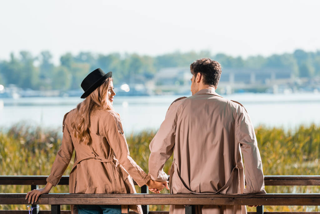 couple in trench coats looking at each other and holding hands - Photo, Image