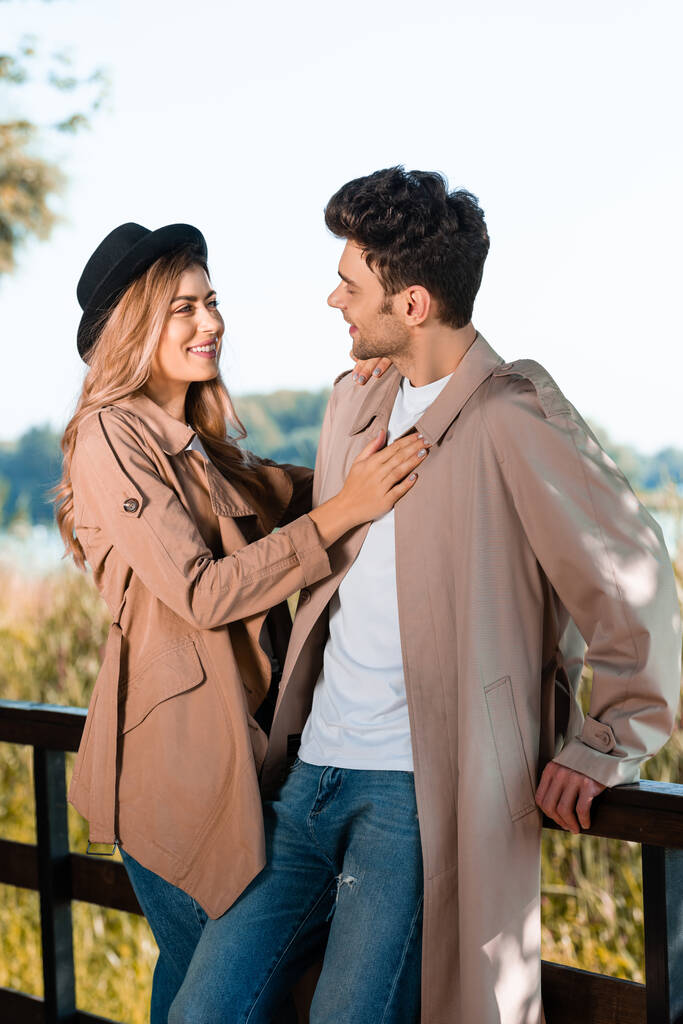 帽子の女性と秋の公園でボーイフレンドに触れるトレンチコート - 写真・画像