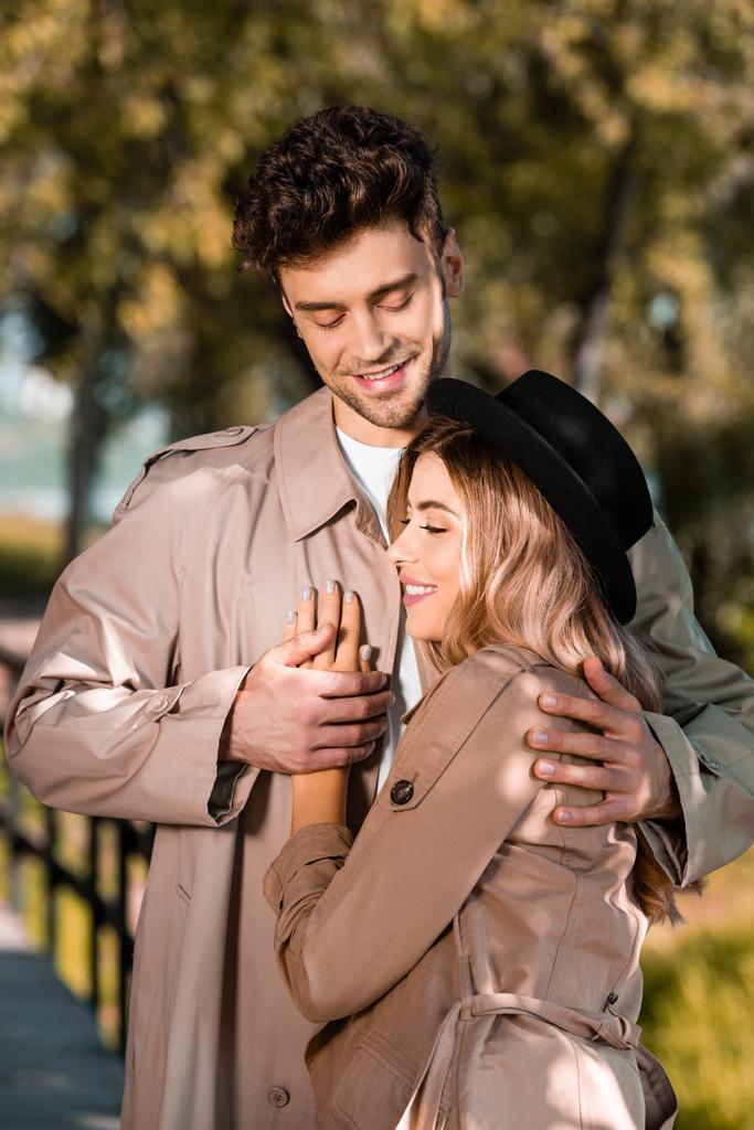 mies trench takki halaus ja koskettava käsi naisen hattu ulkopuolella - Valokuva, kuva