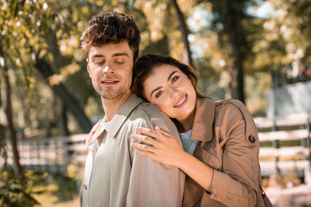 женщина смотрит в камеру и обнимает парня в Осеннем парке  - Фото, изображение