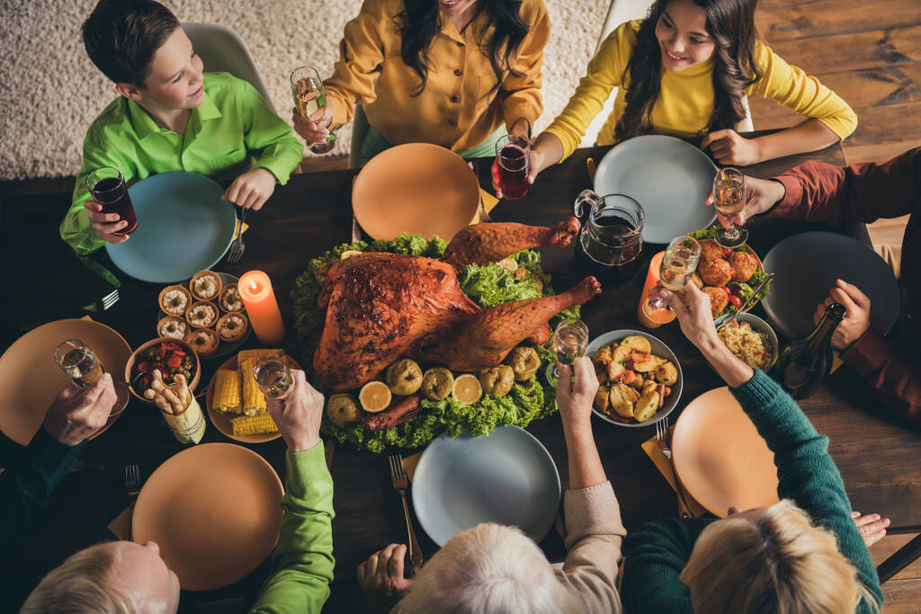 テーブルの周りに座って素敵な魅力的な陽気な優雅な家族の高い角度ビューの上にトリミングされた上おいしい国内食事を楽しむトーストと言っおいしい国内食事近代的なロフト産業木製のインテリアハウス - 写真・画像