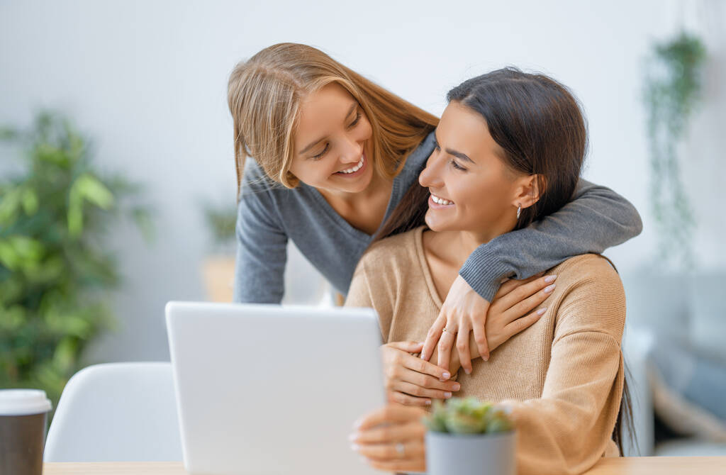 Twee gelukkige jonge vrouwen die laptop gebruiken. Vrienden die samen tijd doorbrengen. - Foto, afbeelding