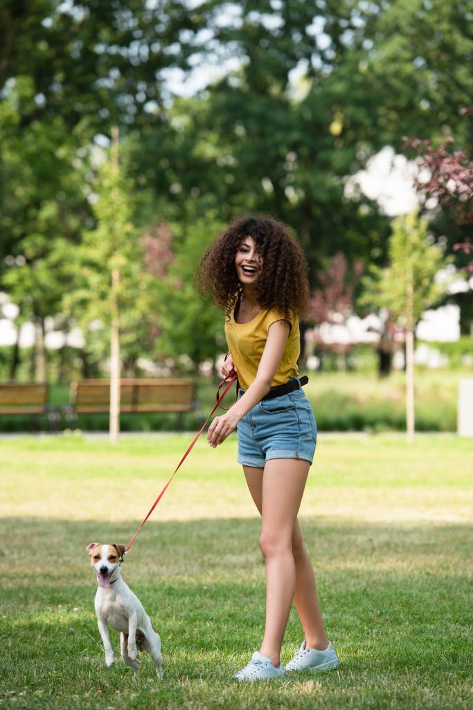 Вибірковий фокус молодої жінки, яка дивиться в сторону і тримає собаку на повідку
 - Фото, зображення