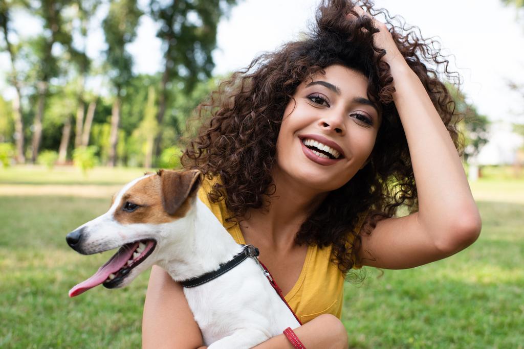 Selective focus of young woman touching hair and holding dog - Photo, Image