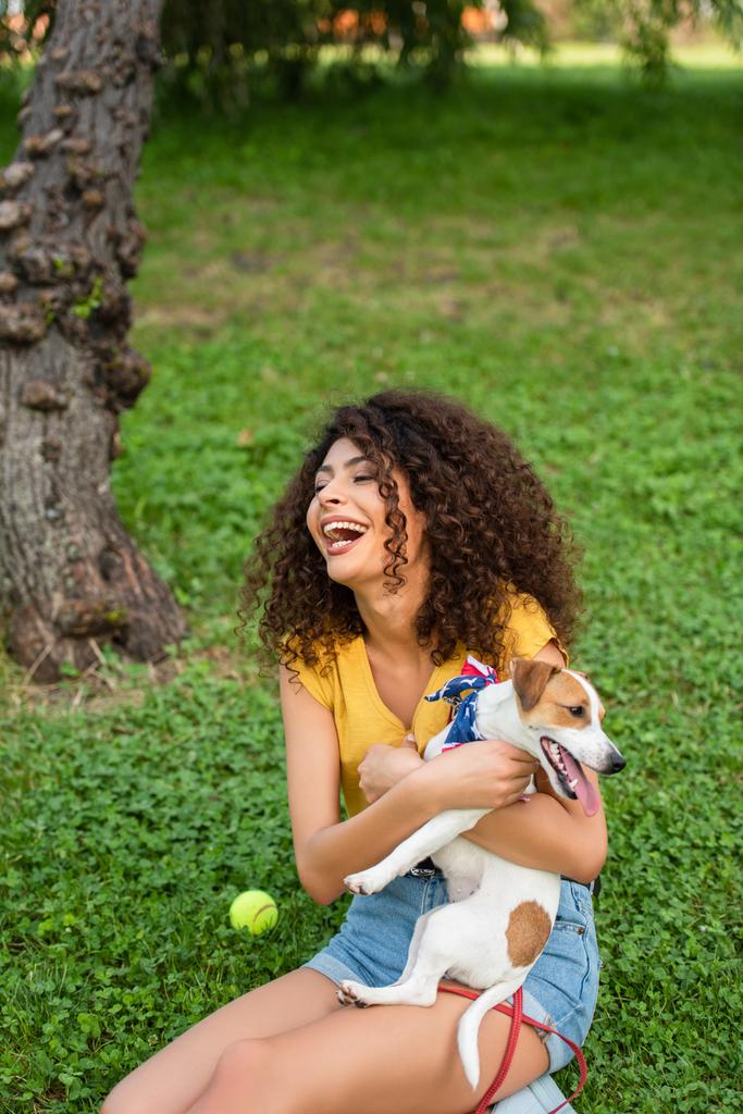 Foco seletivo de mulher animado sentado com Jack Russell terrier cão na grama - Foto, Imagem