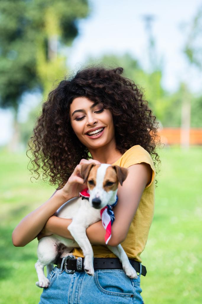 επιλεκτική εστίαση του χαρούμενη, σγουρά γυναίκα χαϊδεύοντας Jack Russell terrier σκυλί - Φωτογραφία, εικόνα