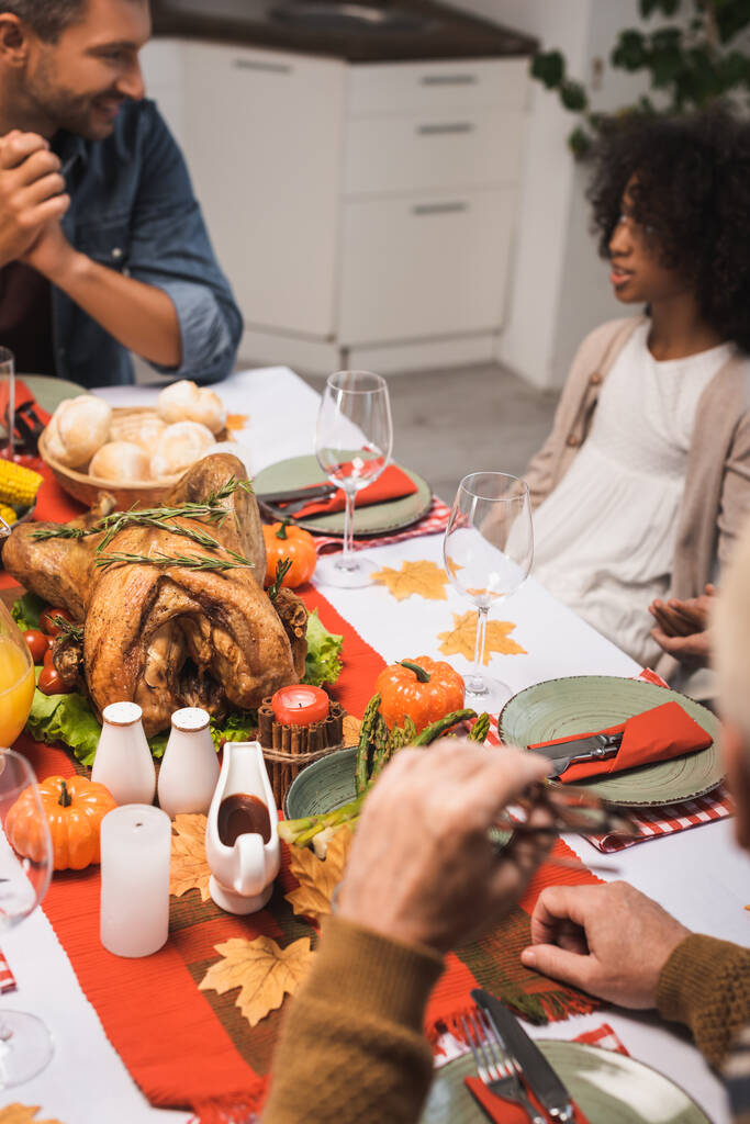 focalizzazione selettiva dell'uomo che parla con la figlia afroamericana durante la cena del Ringraziamento con la famiglia - Foto, immagini