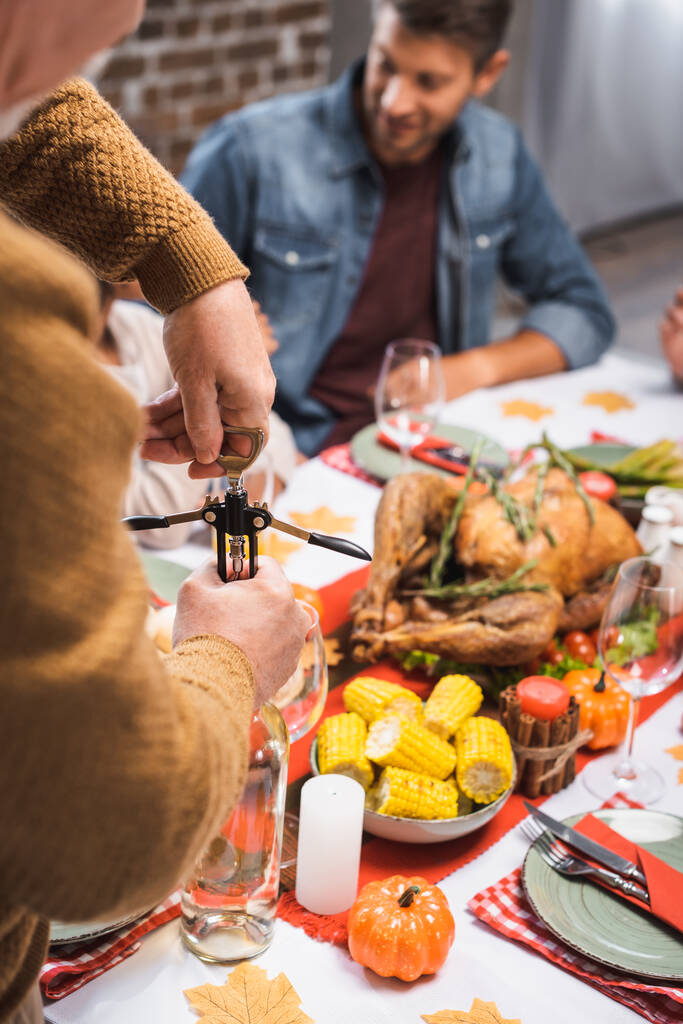 selektywne skupienie się seniora otwierającego butelkę białego wina podczas święta dziękczynienia z rodziną - Zdjęcie, obraz