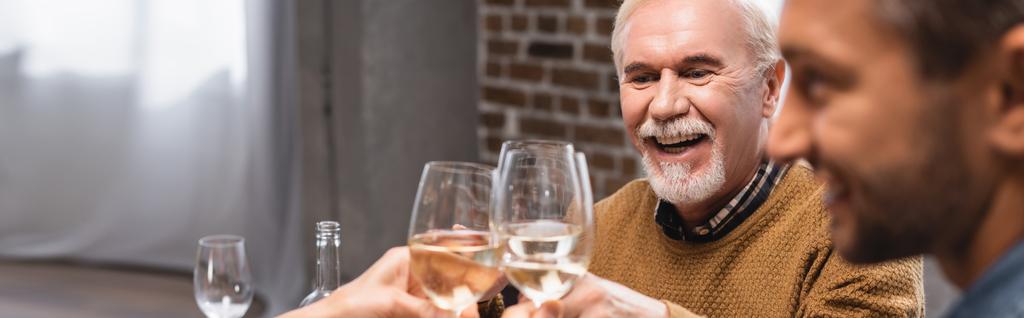 επιλεκτική εστίαση ενθουσιασμένοι πατέρας και γιος clinking ποτήρια λευκό κρασί κατά τη διάρκεια των ευχαριστιών γιορτή, πανοραμική καλλιέργεια - Φωτογραφία, εικόνα