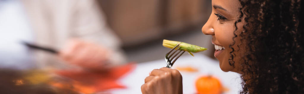 感謝祭の間にアスパラガスを食べるアフリカ系アメリカ人女性のパノラマ写真  - 写真・画像