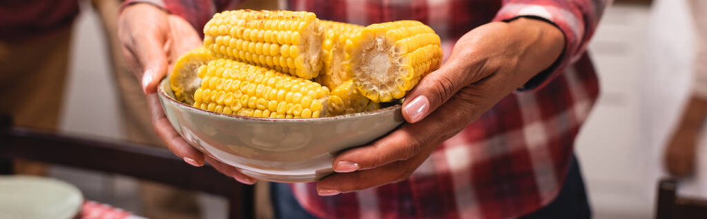 Cultivo panorámico de mujer afroamericana sosteniendo tazón de maíz en casa  - Foto, Imagen