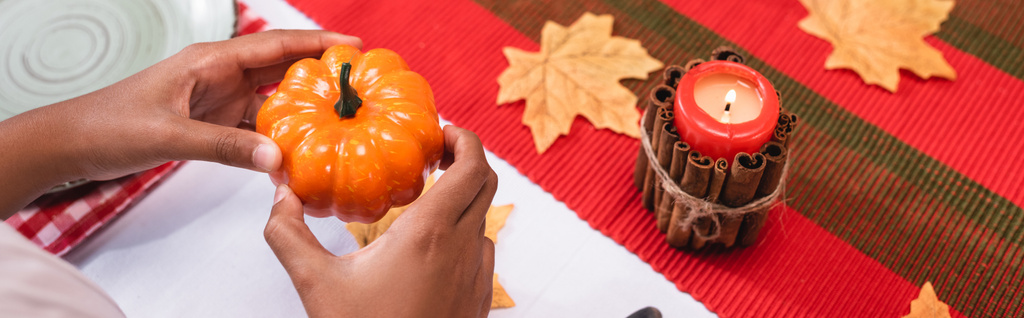 Panoramic shot of african american girl holding decorative pumpkin near candle during thanksgiving  - Photo, Image