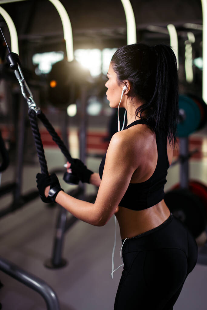 zadní pohled fit žena provádět cvičení s cvičením-stroj Cable Crossover v tělocvičně - Fotografie, Obrázek