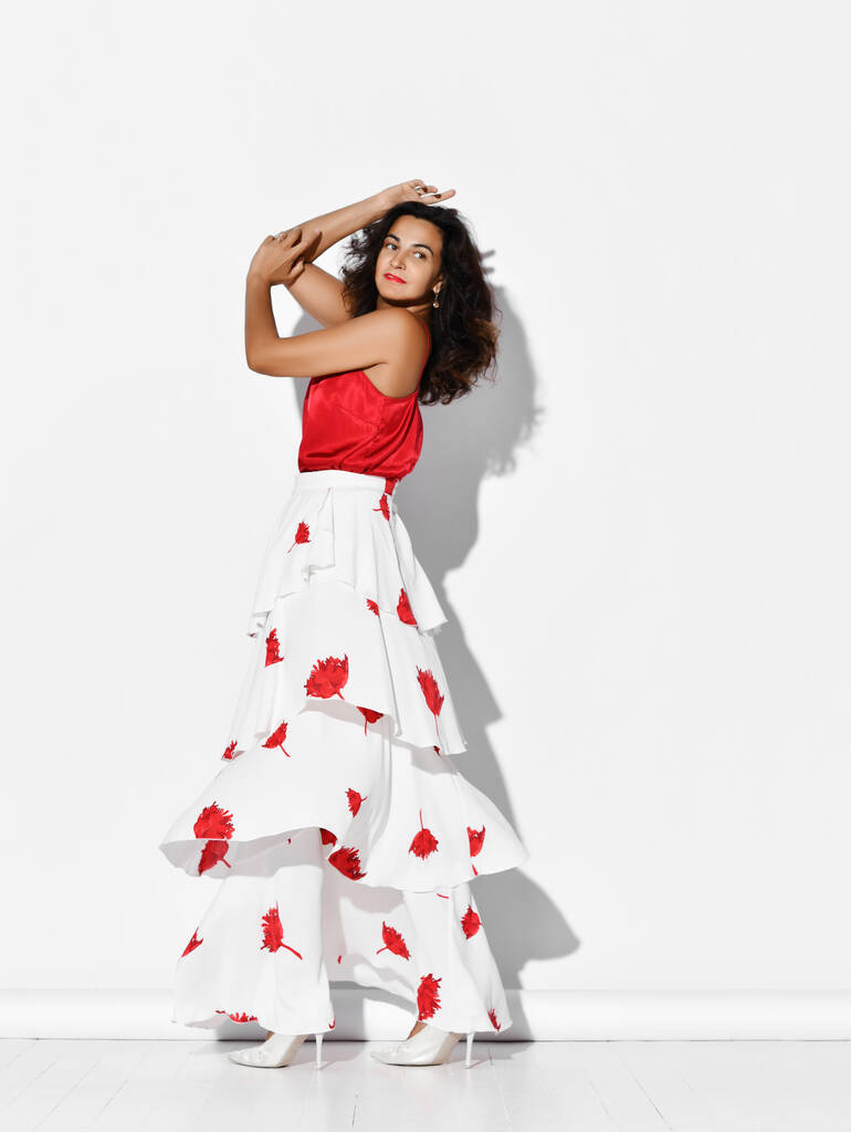 Preciosa bailarina hispana vestida de rojo blanco con estampados florales Carmen flamenco de la mano en la cabeza - Foto, Imagen