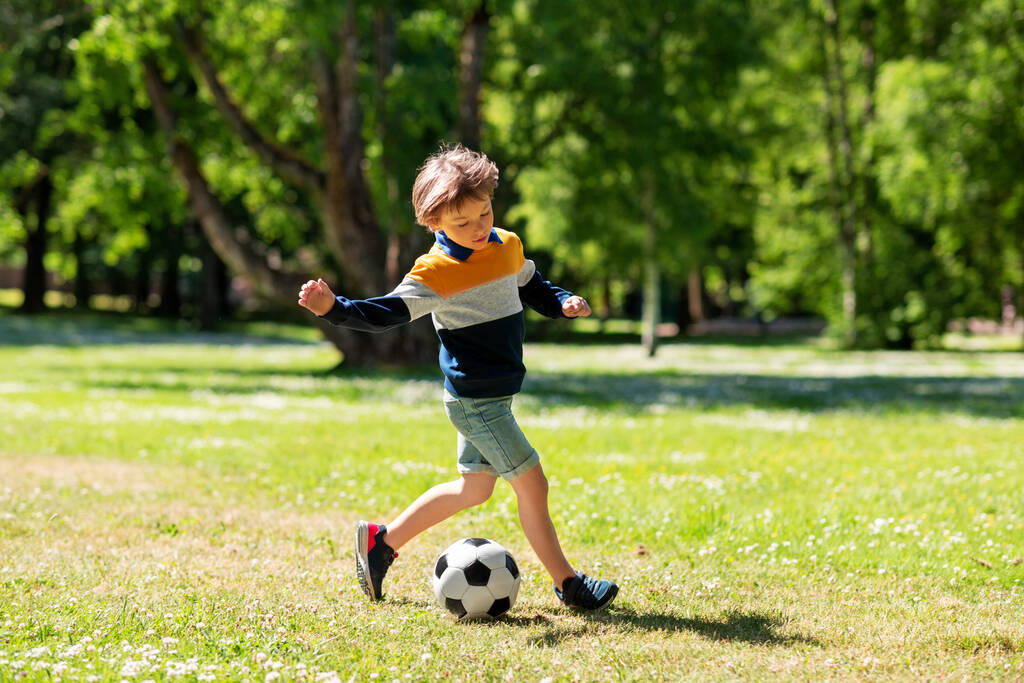 щасливий маленький хлопчик з м'ячем грає у футбол у парку
 - Фото, зображення
