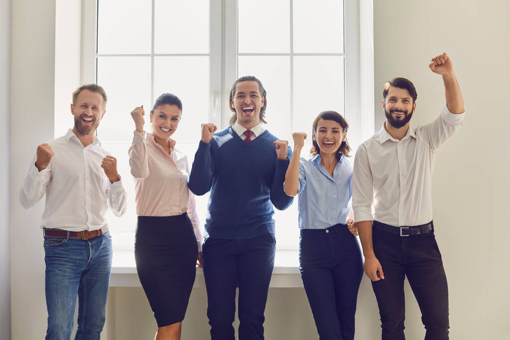 Группа улыбчивых деловых людей, выражающих успешную командную работу или реализацию проектов в офисе - Фото, изображение