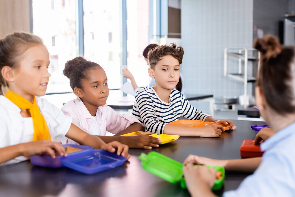 selektivní zaměření multikulturních žáků sedících ve školní jídelně u občerstvení - Fotografie, Obrázek