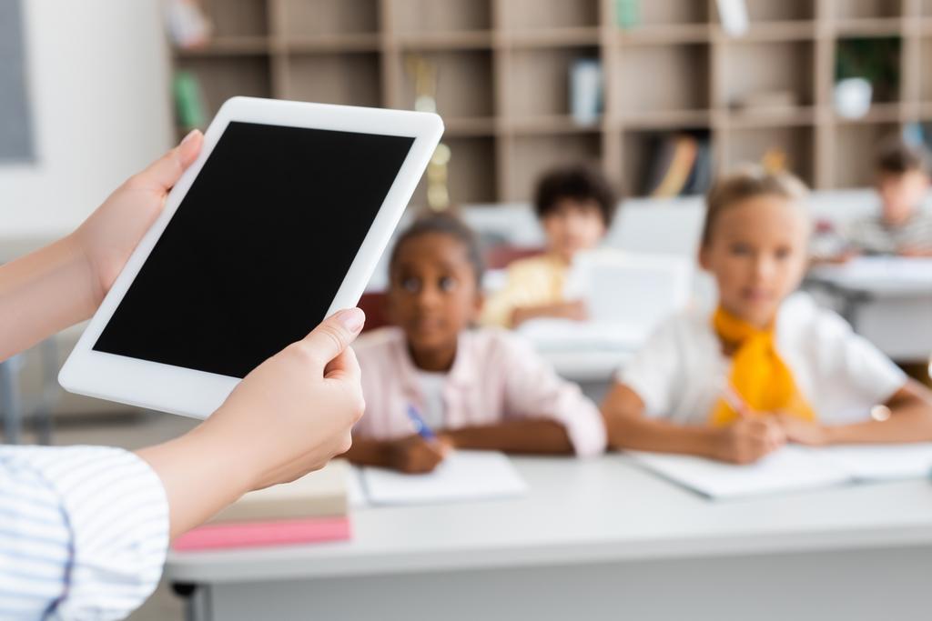 частковий вид вчителя, що тримає цифровий планшет з порожнім екраном біля мультикультурних учнів
 - Фото, зображення
