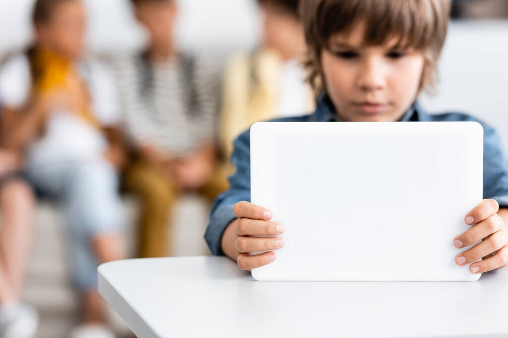 Concentration sélective de l'écolier en utilisant une tablette numérique au bureau dans la salle de classe  - Photo, image