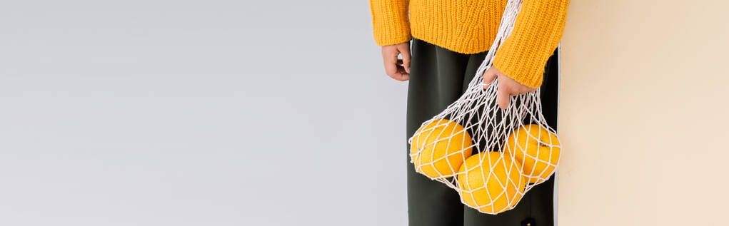 vista cortada da menina na moda em roupa de outono posando com toranjas em saco de corda no fundo bege e branco, tiro panorâmico - Foto, Imagem