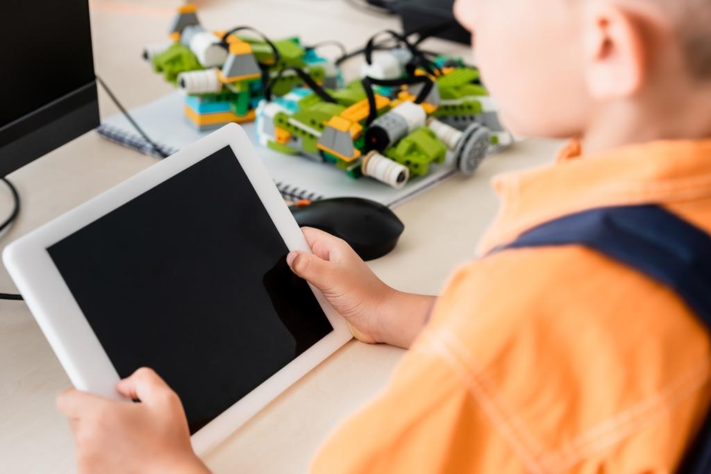 Gekropte weergave van schooljongen met digitale tablet in stamschool  - Foto, afbeelding