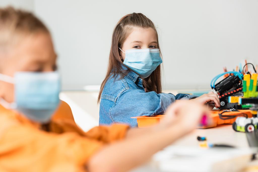 Selectieve focus van schoolkinderen in medische maskers die robots bouwen in de stamschool  - Foto, afbeelding