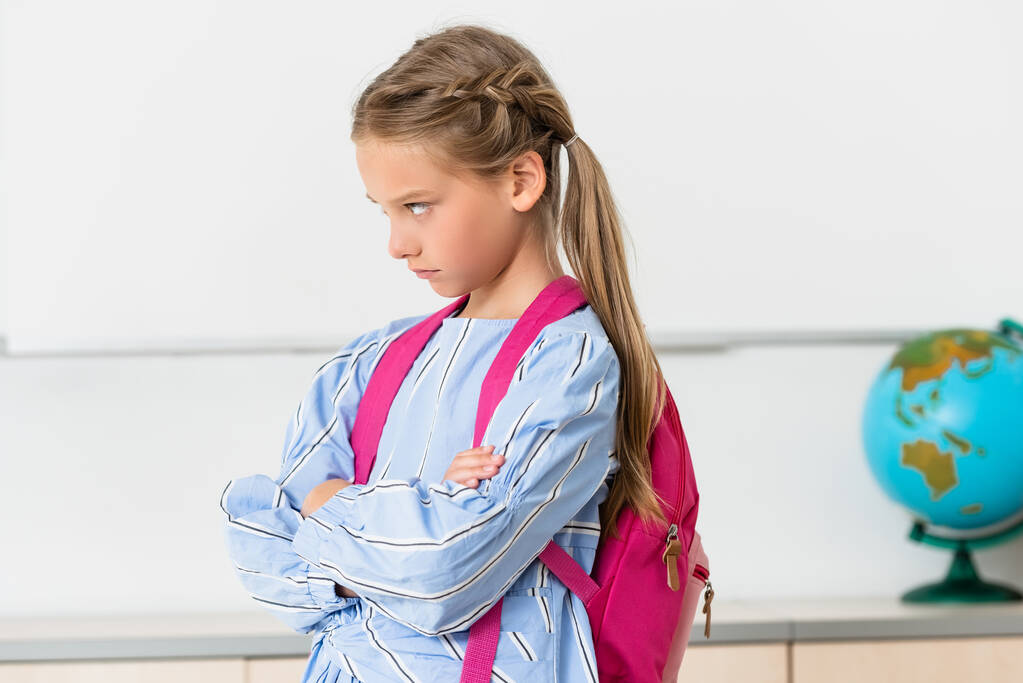 Σοβαρή μαθήτρια με σακίδιο που κοιτάει αλλού στην τάξη  - Φωτογραφία, εικόνα