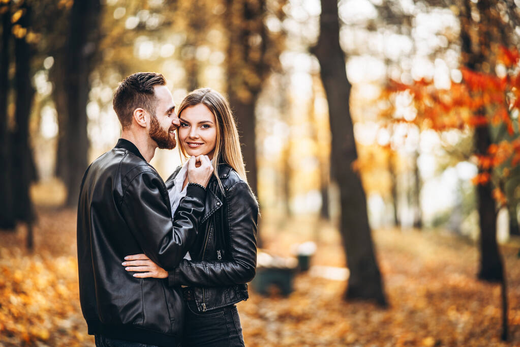 Portret młodej kochającej się pary. Mężczyzna i kobieta przytulają się i uśmiechają w tle jesiennego parku. - Zdjęcie, obraz