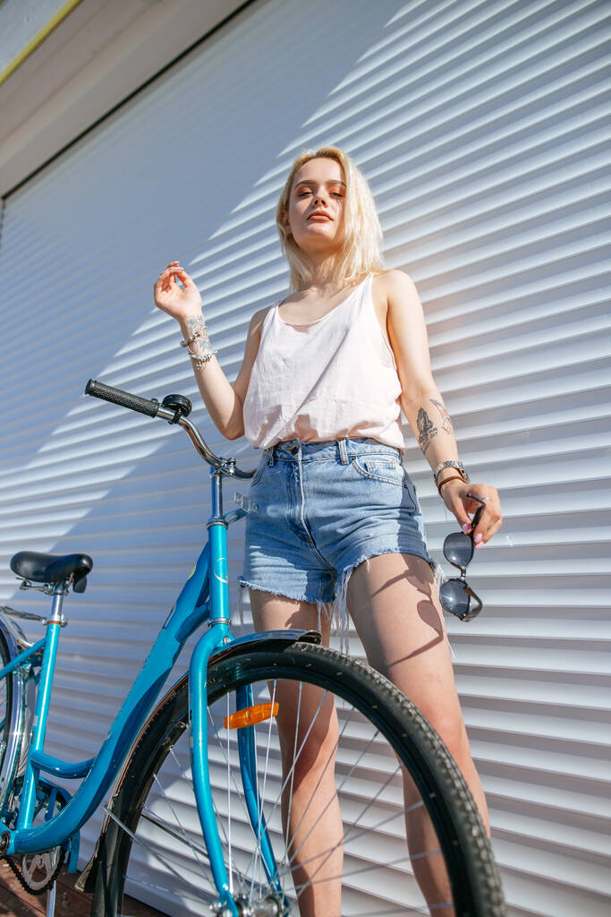 Жінка з світлим волоссям біля велосипеда ізольована на білому тлі
. - Фото, зображення