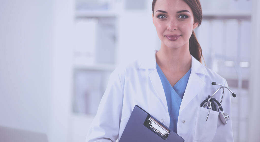 Muotokuva nuori nainen lääkäri valkoinen takki seisoo sairaalassa - Valokuva, kuva