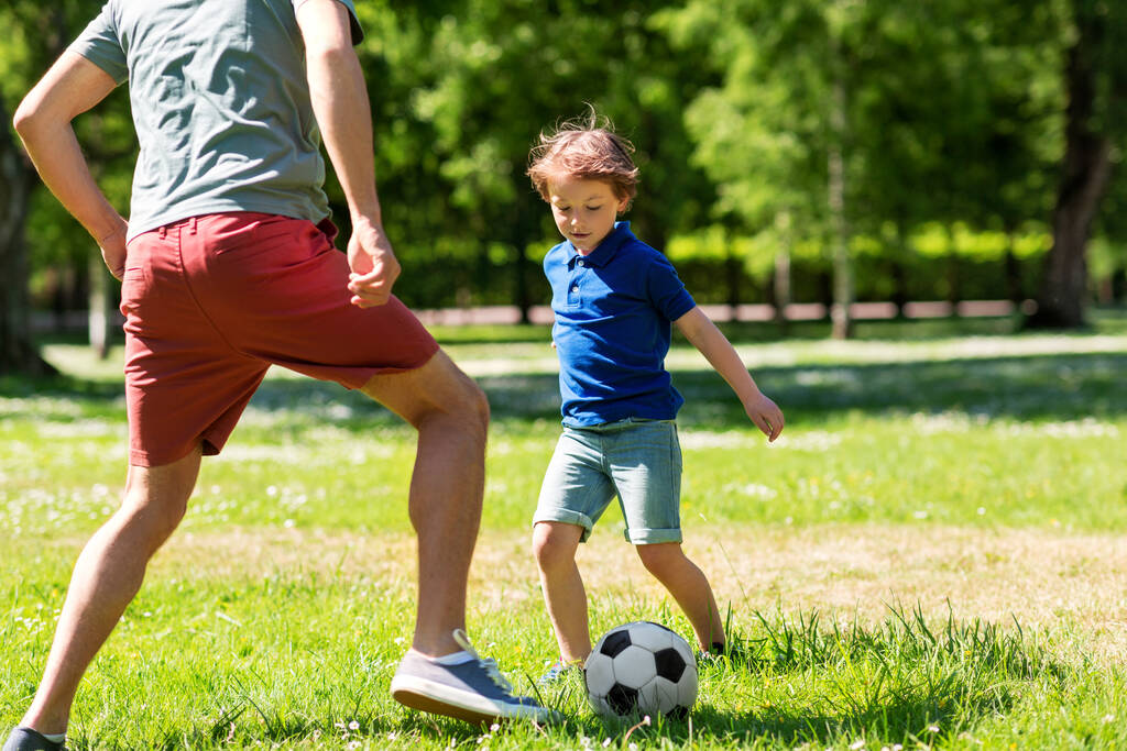 幼い息子が公園でサッカーをしている父親 - 写真・画像