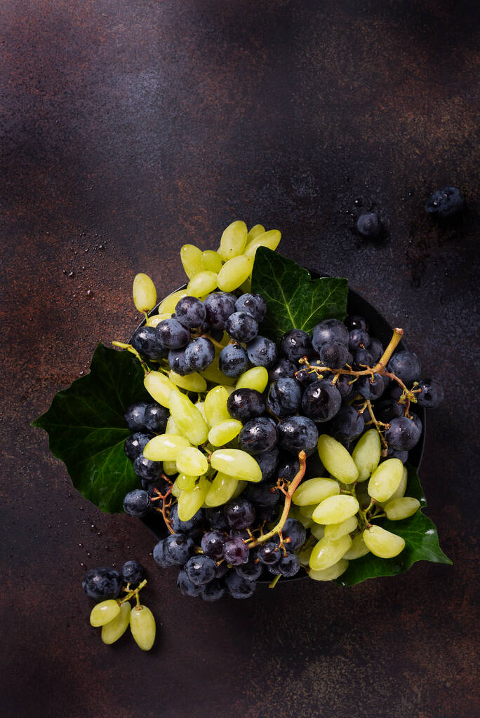 Mix di uva bianca e nera sullo sfondo scuro, vista dall'alto verso il basso con spazio di copia per il testo - Foto, immagini