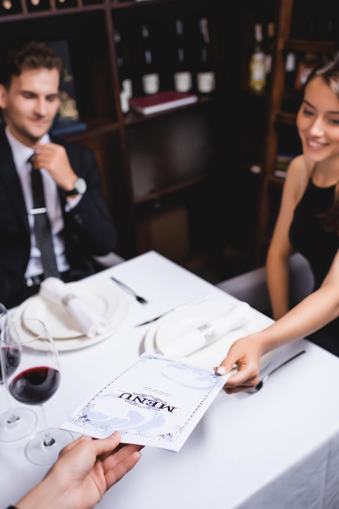 Selective focus of waiters giving menu to woman at table in restaurant - Photo, Image