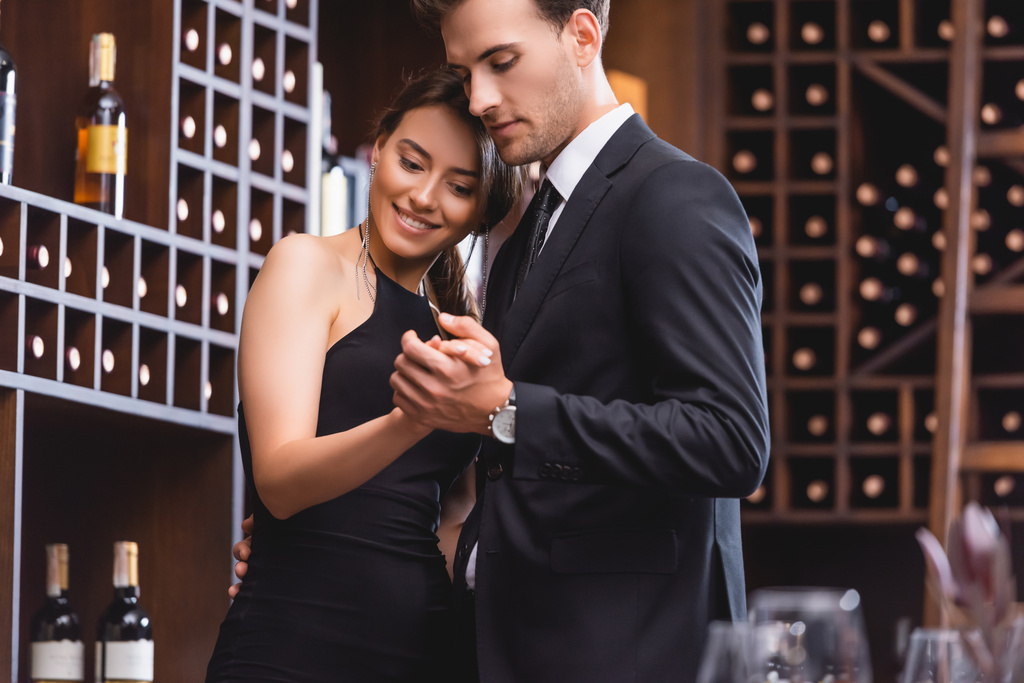 Selective focus of young man in suit dancing with elegant girlfriend in restaurant  - Photo, Image