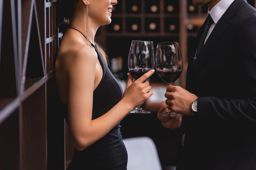 Cropped view of elegant woman holding glass of wine near boyfriend in suit in restaurant  - Photo, Image
