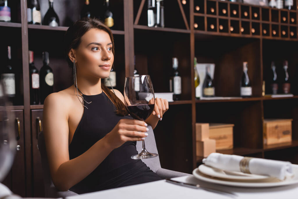 Вибірковий фокус елегантної жінки, що тримає келих вина за столом у ресторані
  - Фото, зображення