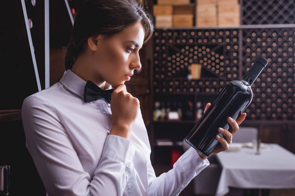 Pensive sommelier met fles wijn in restaurant  - Foto, afbeelding