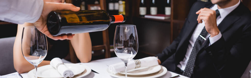 レストランのカップルの近くのガラスにワインを注ぐソムリエのウェブサイトのヘッダー ロイヤリティフリー写真 画像素材