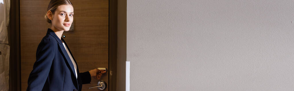 πανοραμική έννοια της businesswoman στο κοστούμι κρατώντας κάρτα δωματίου, ενώ ξεκλείδωμα πόρτα στο ξενοδοχείο  - Φωτογραφία, εικόνα