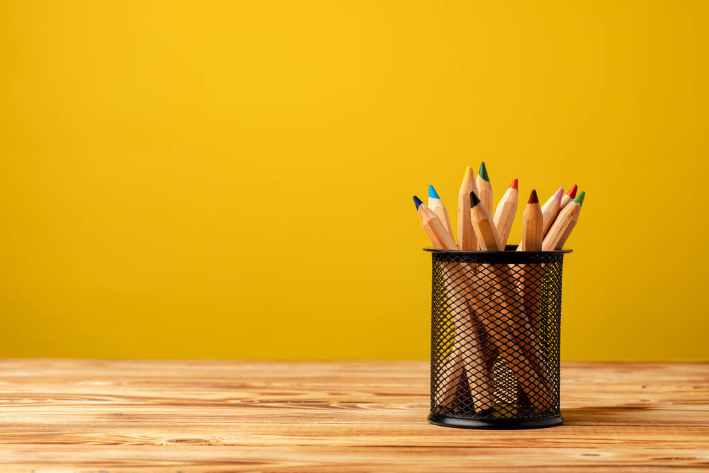 Taza de oficina con lápices y papelería sobre fondo amarillo - Foto, imagen