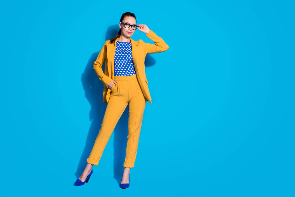 Повна довжина фотографії привабливої бізнес-леді успішний працівник тримає ручний зір читання окуляри носити жовтий костюм блейзер пунктирна блузка сорочка ізольований яскраво-синій кольоровий фон
 - Фото, зображення
