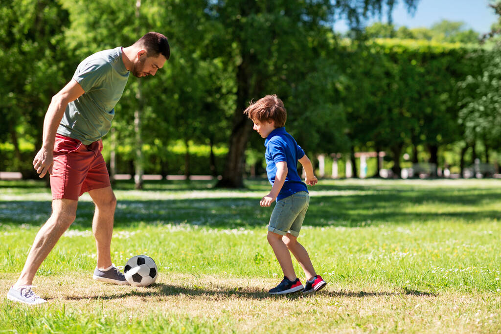 Isä pienen poikansa kanssa pelaamassa jalkapalloa puistossa - Valokuva, kuva