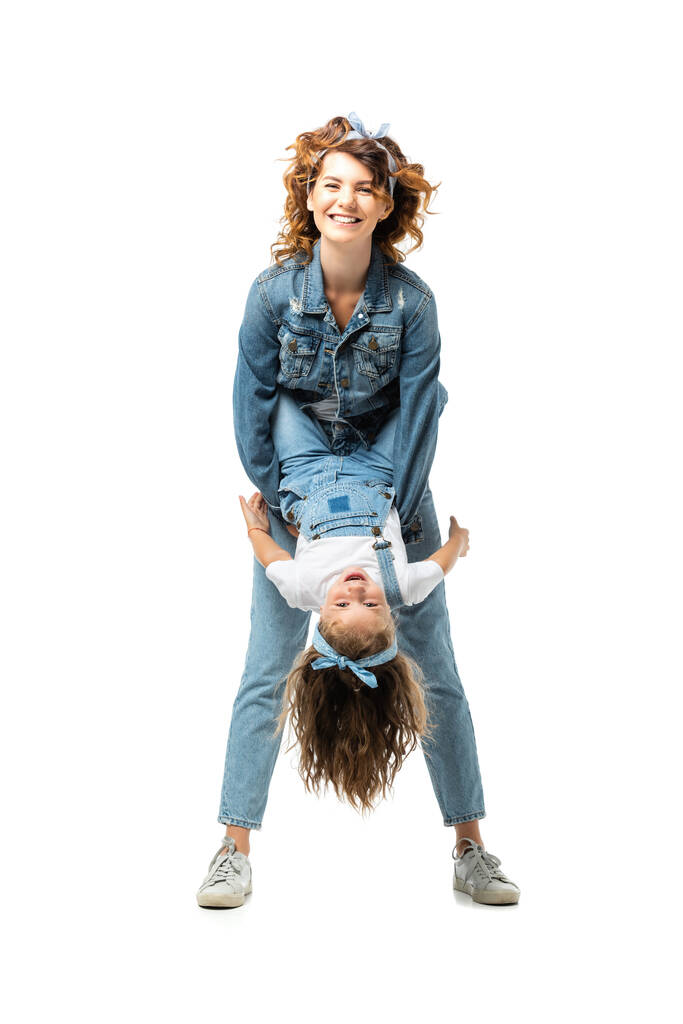 Mutter und Tochter im Jeans-Outfit amüsieren sich isoliert auf Weiß - Foto, Bild