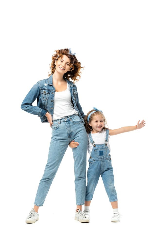 Tochter im Jeans-Outfit umarmt Mutter Bein mit ausgestreckter Hand isoliert auf weiß - Foto, Bild