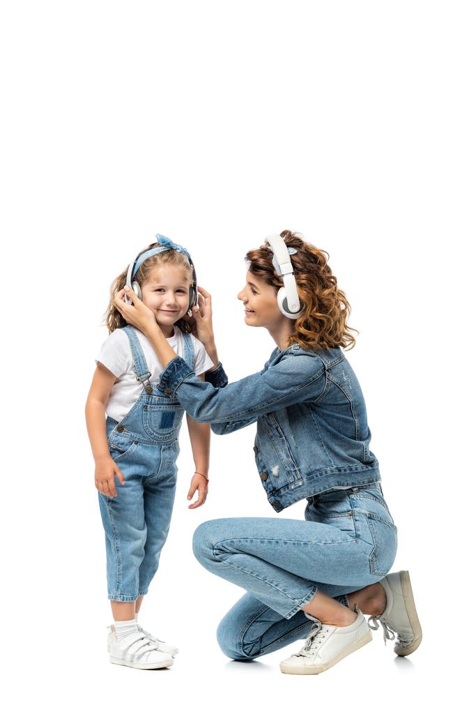 мати і дочка в джинсових костюмах слухають музику в навушниках ізольовані на білому
 - Фото, зображення