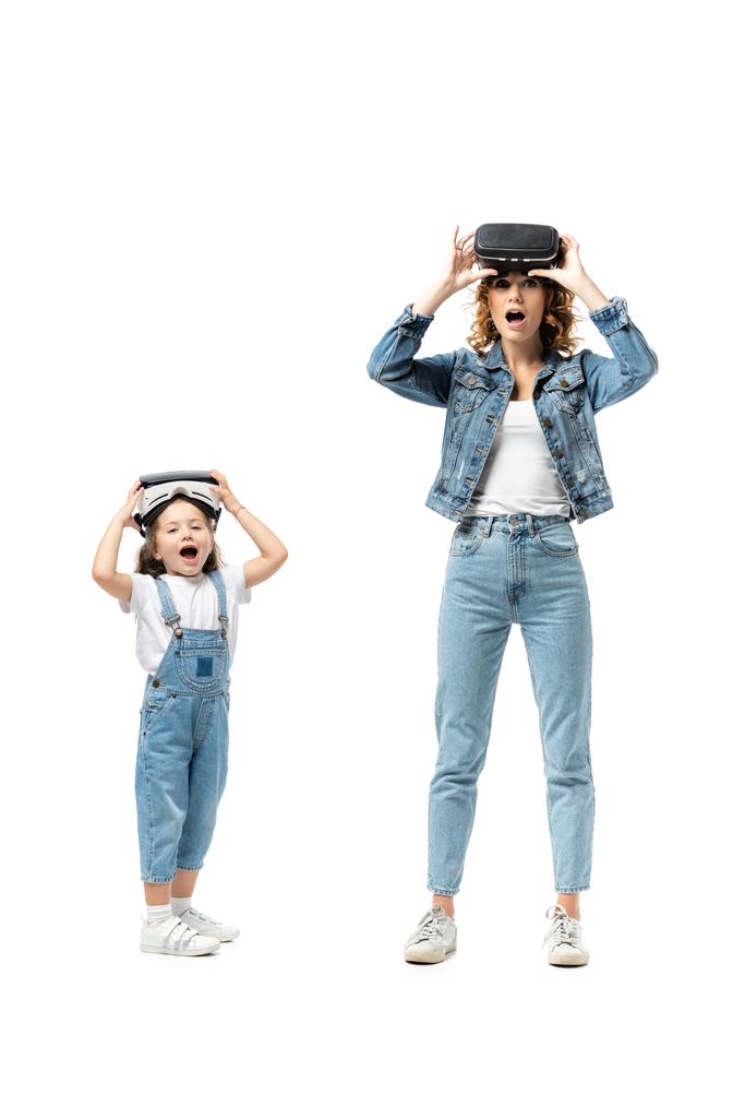 mãe chocada e filha em trajes de ganga e fones de ouvido realidade virtual isolados em branco - Foto, Imagem