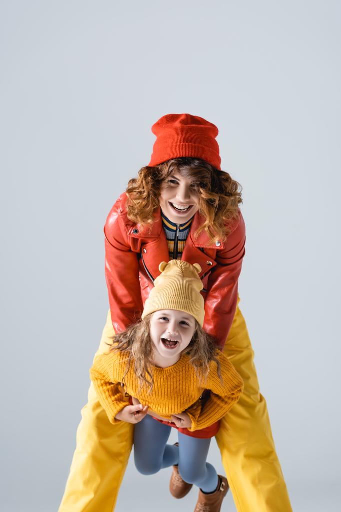 mother and daughter in colorful red and yellow outfits smiling isolated on grey - Photo, Image